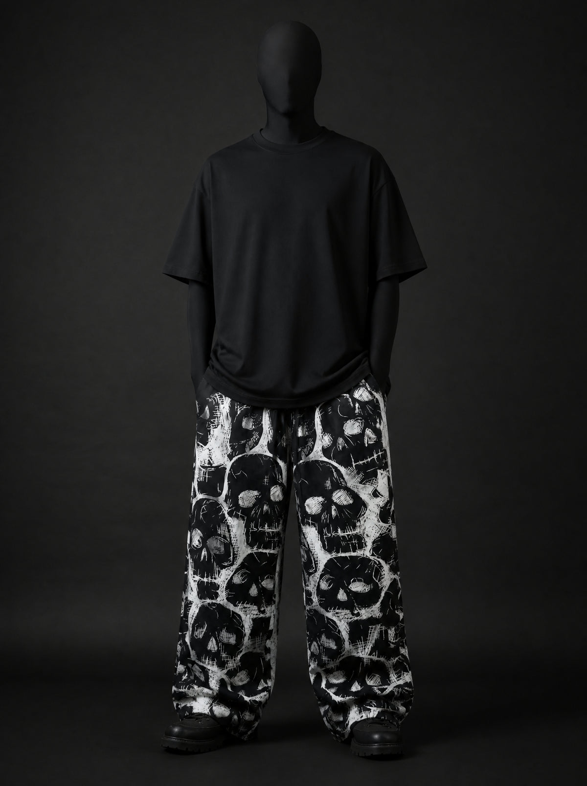 Full-length front view of model in black oversized tee and baggy black and white skull print pants