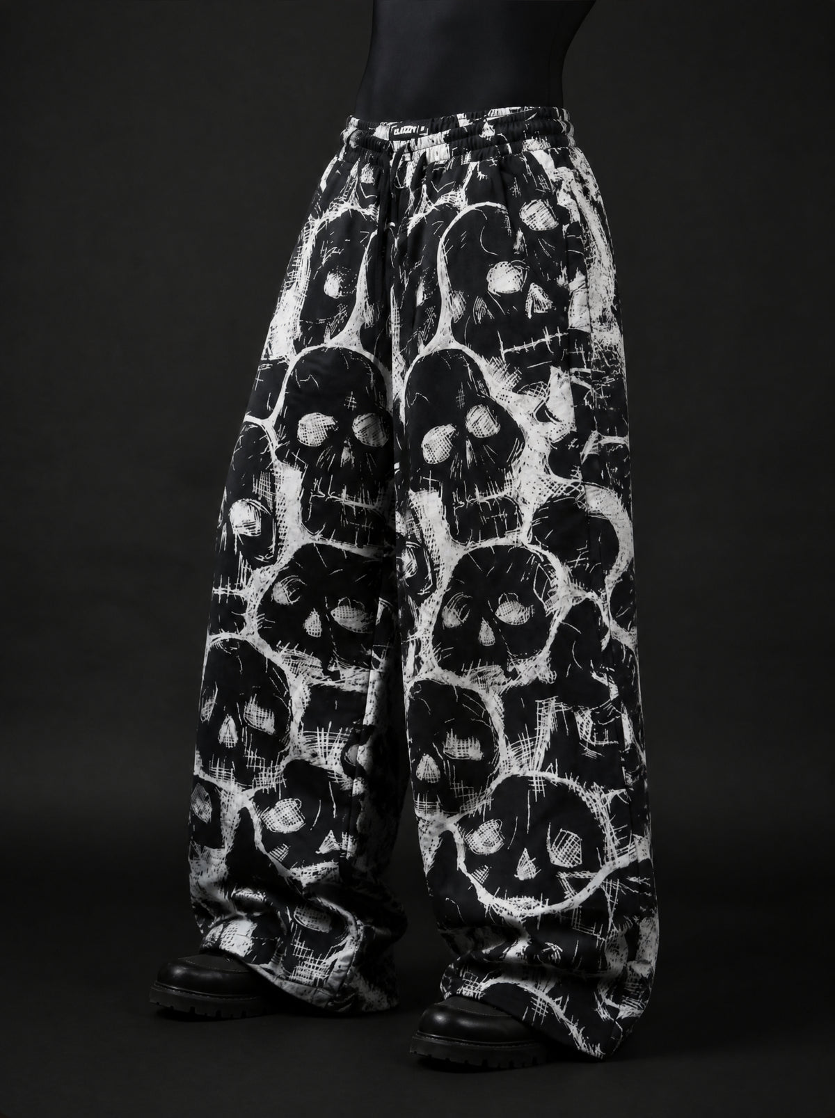 Angled front view of wide-leg skull print pants with drawstring elastic waistband, worn with black boots
