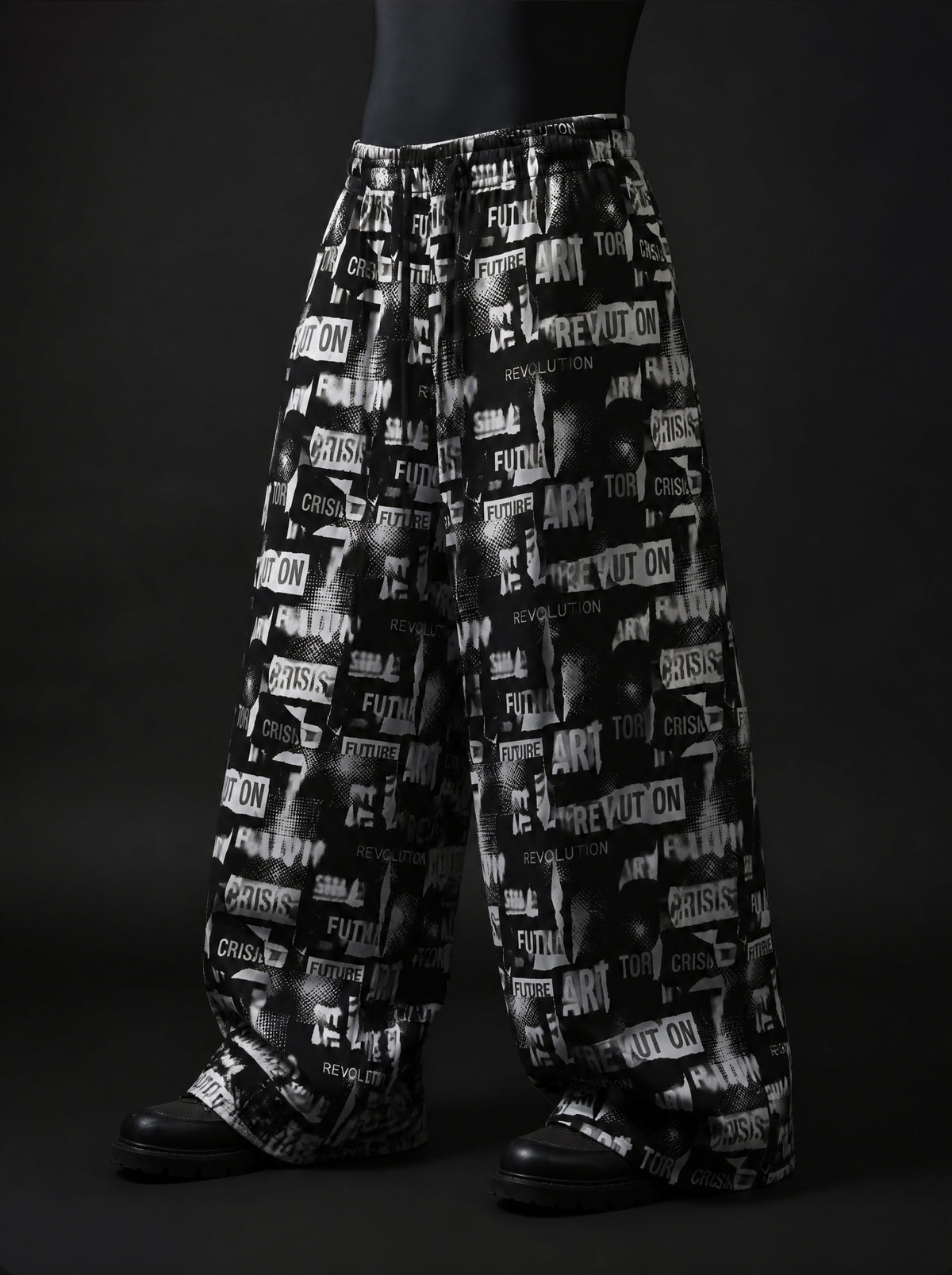 Three-quarter view of baggy drawstring pants with black and white collage print of words like ART and REVOLUTION
