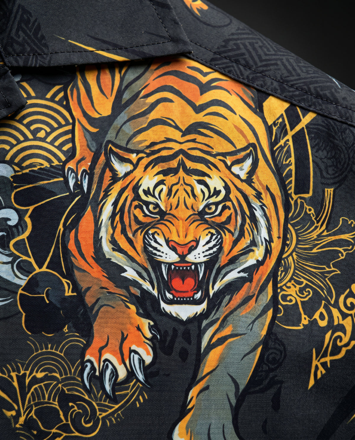 Close-up of snarling orange tiger print with gold patterns and stitched collar on black fabric