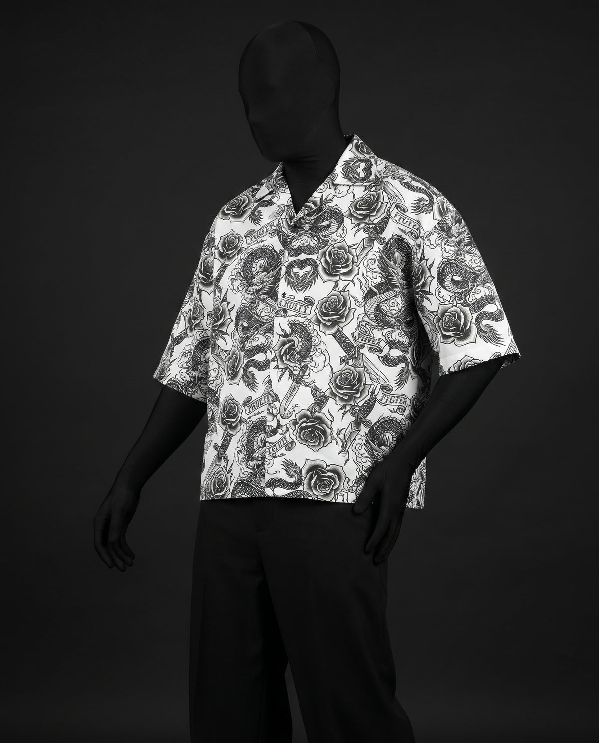 Three-quarter front view of boxy white Cuban collar shirt with black dragon, rose and banner print on mannequin
