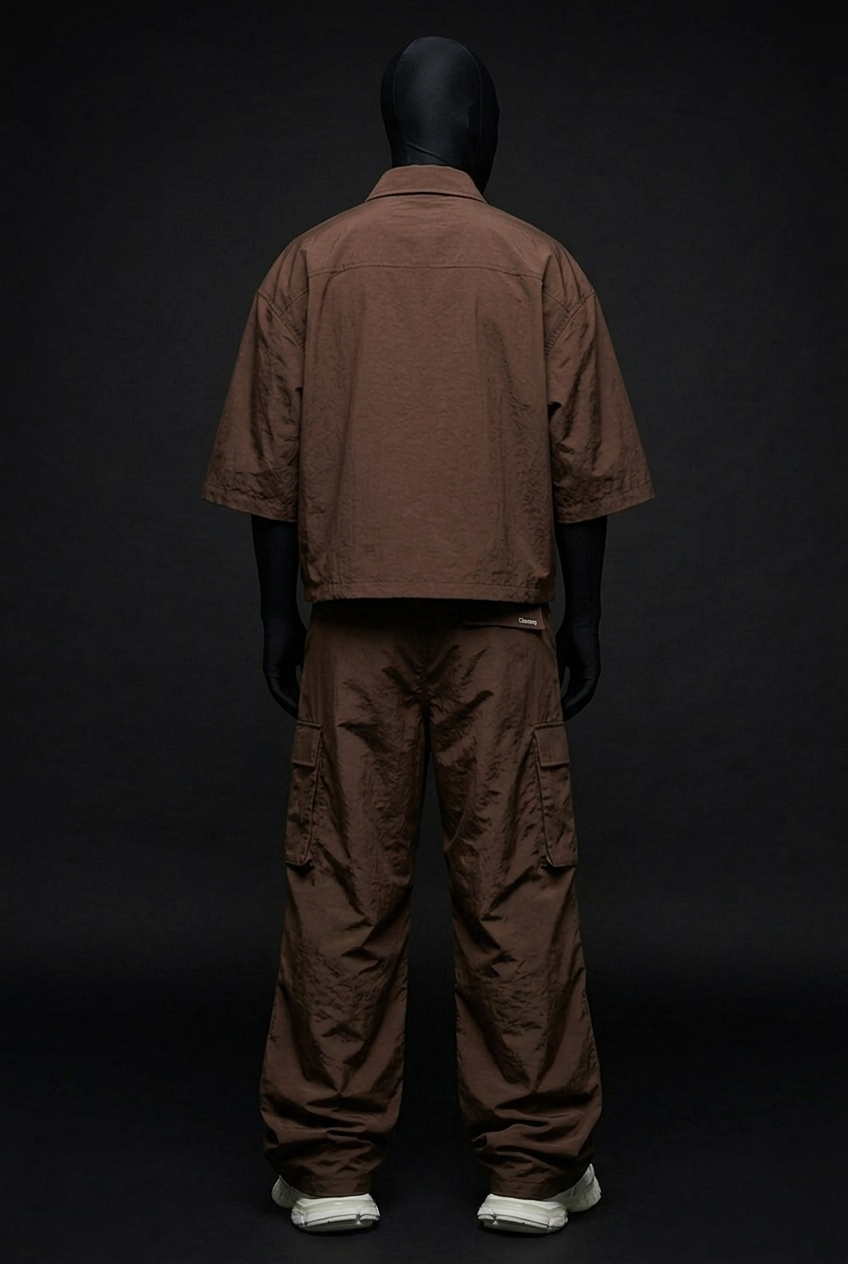 Back view of model in brown boxy short-sleeve shirt and cargo pants with small label