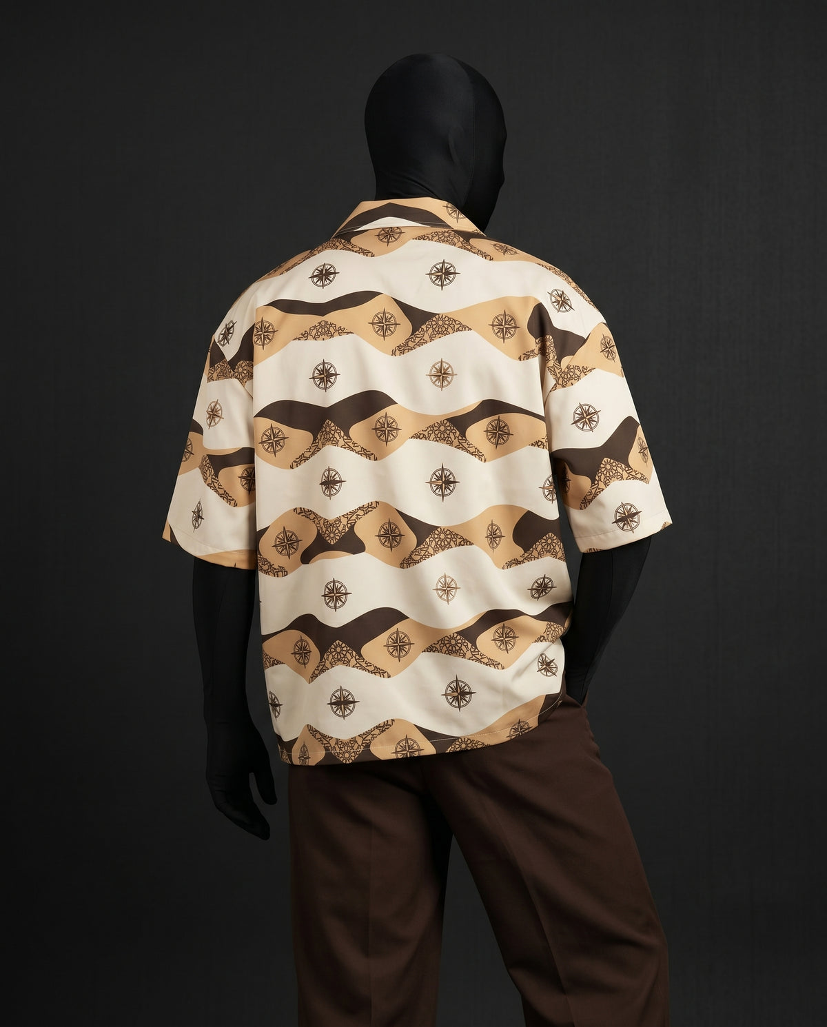 Back view of boxy short-sleeve shirt with brown and tan wave stripes and compass motifs on mannequin