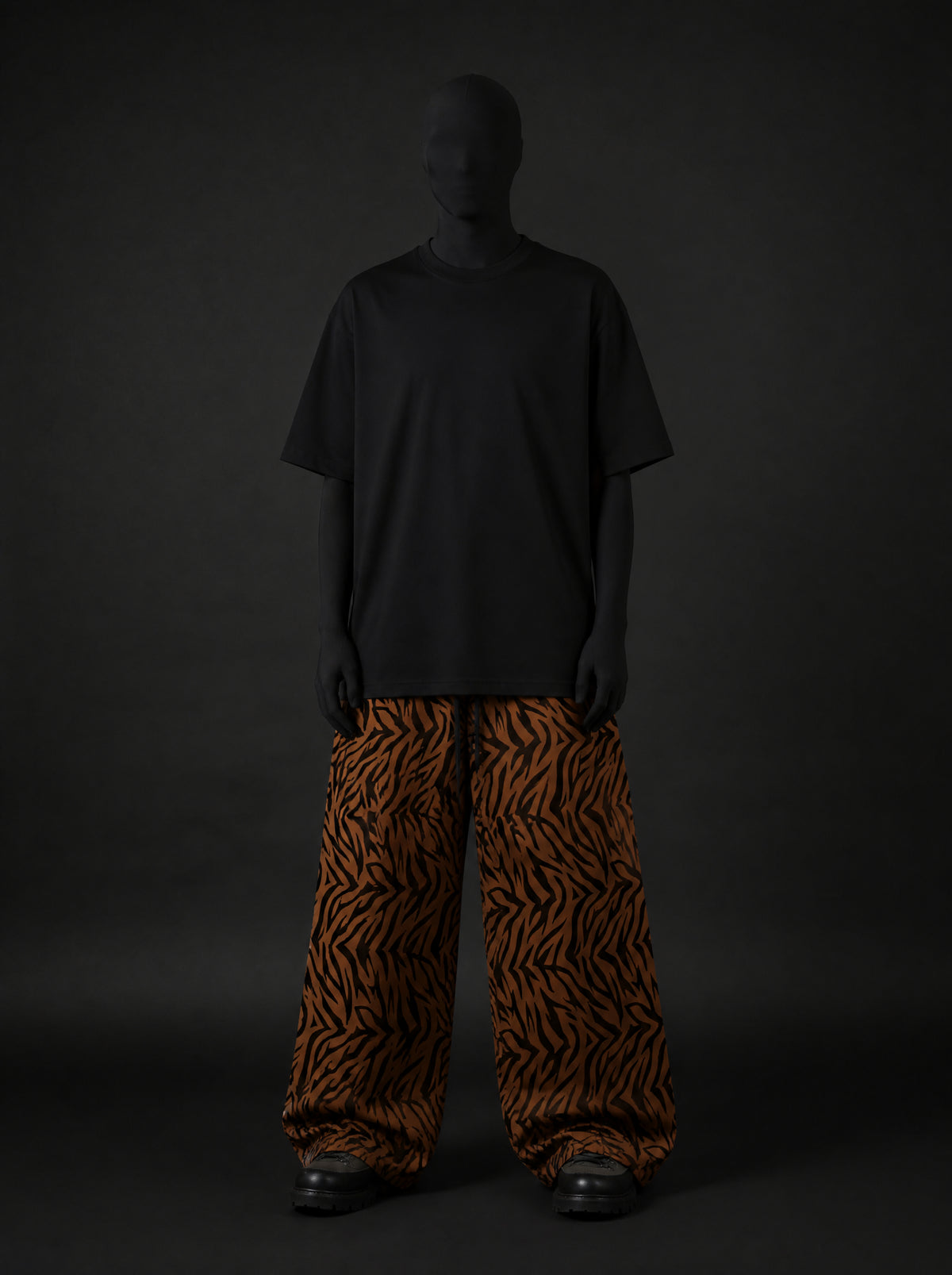 Full-length front view of a model in black oversized tee and wide-leg tiger-stripe pants