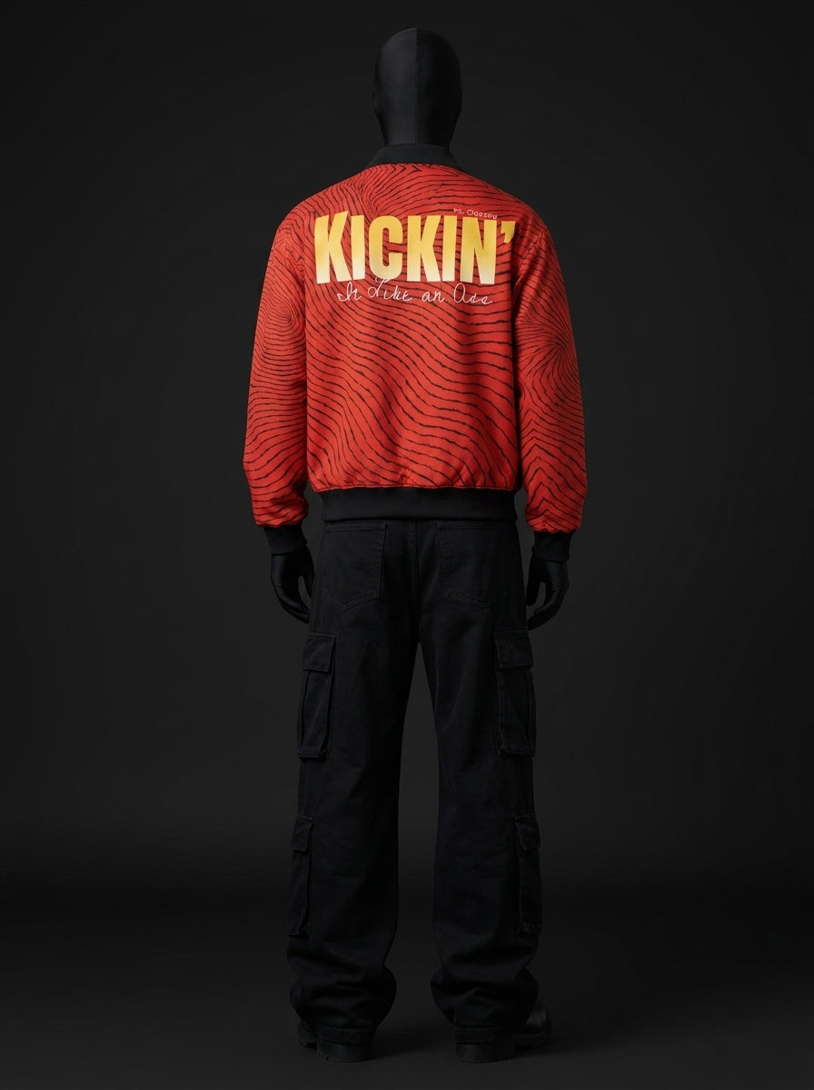 Back view of red wave-print jacket with yellow "KICKIN'" lettering and script text, worn with black cargo pants