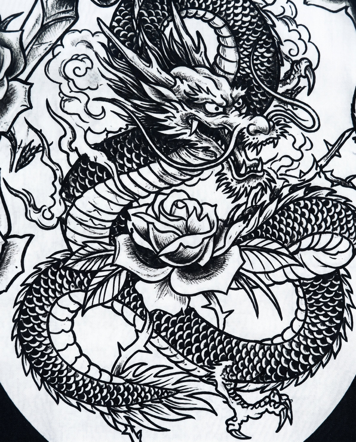 Close-up of black ink dragon coiled around a rose on white shirt fabric