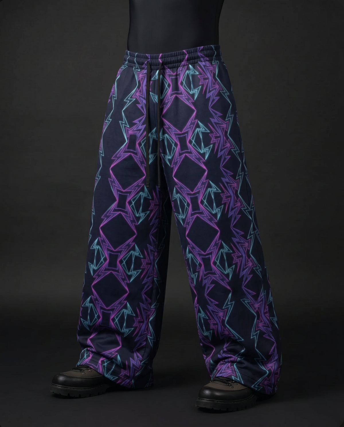 Three-quarter front view of baggy navy pants with purple and teal zigzag diamond print and drawstring waist