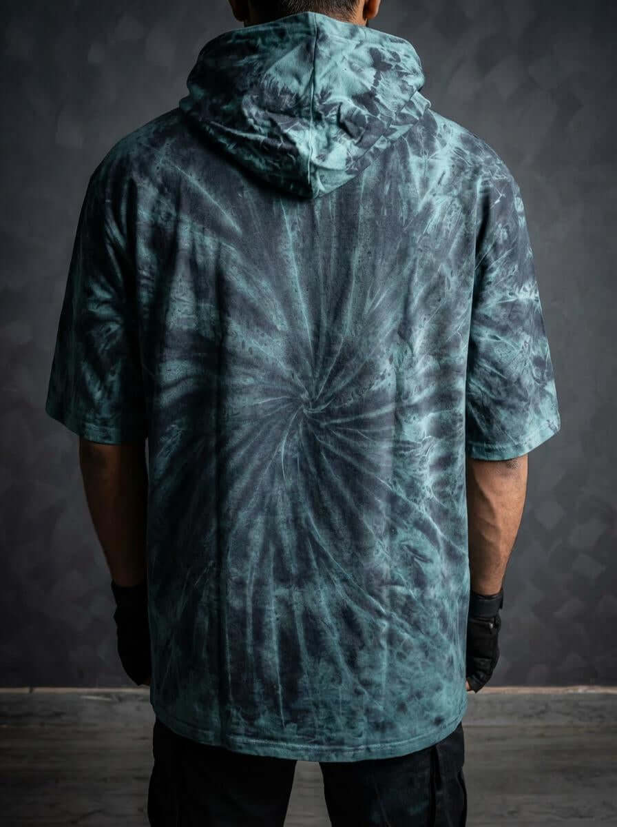 Back view of model in teal and black spiral tie-dye short-sleeve hooded top and black pants