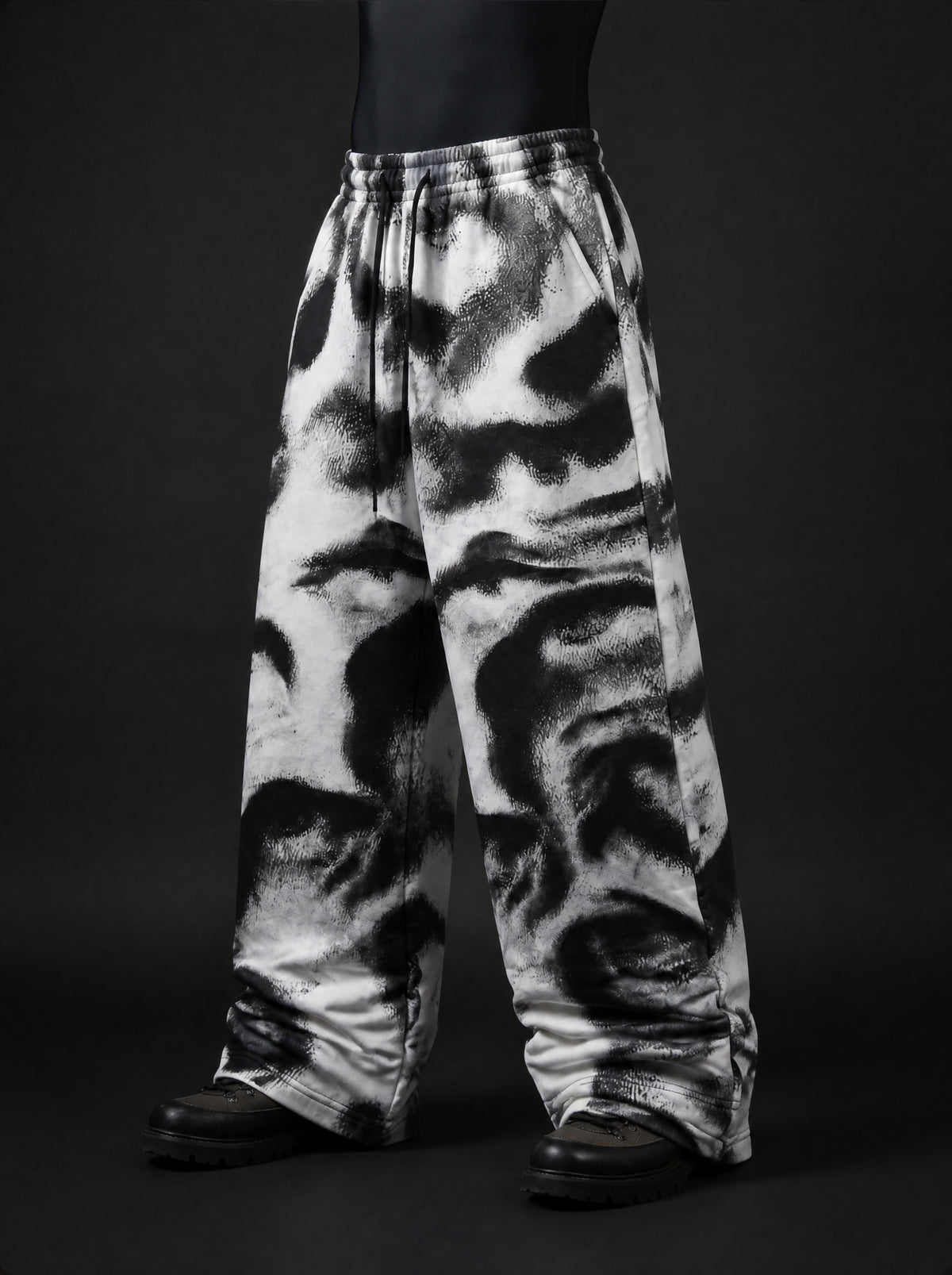 Three-quarter view of baggy drawstring pants with black and white smudged abstract print and side pocket