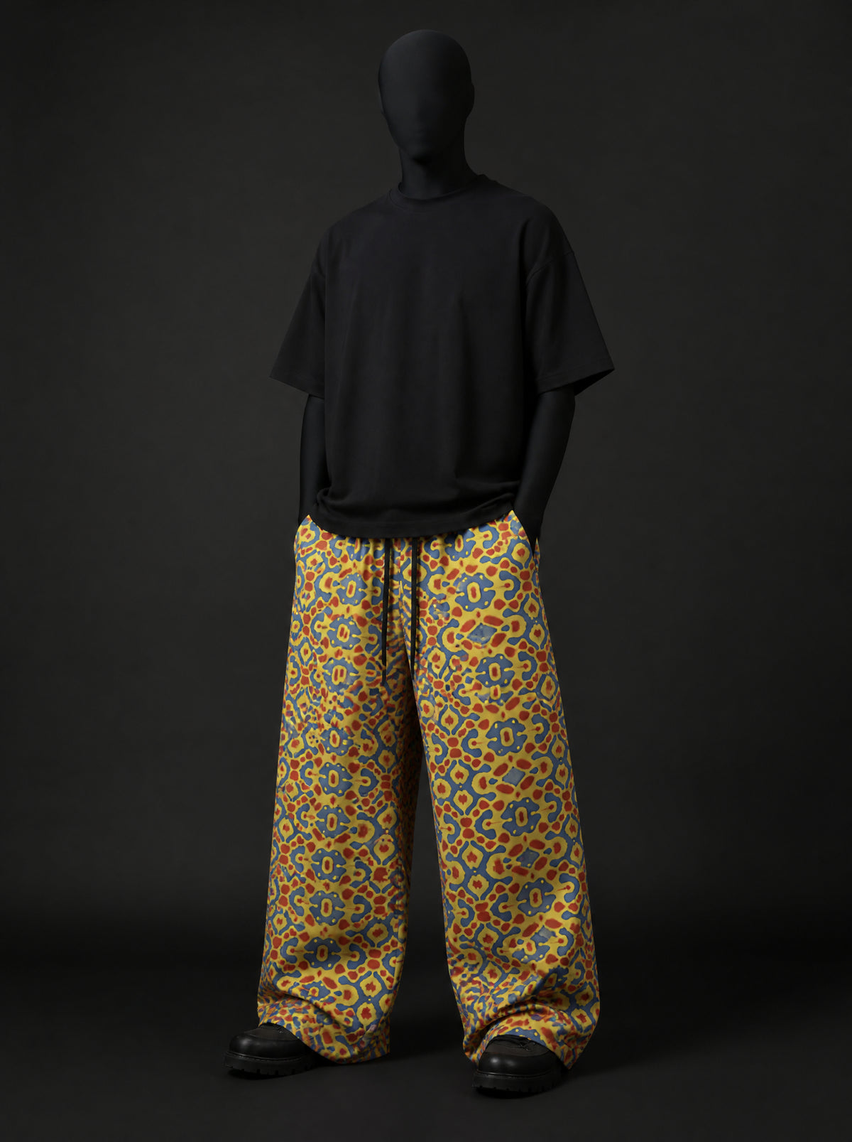 Full-length front view of mosaic-print wide-leg pants worn with an oversized black t-shirt and black boots