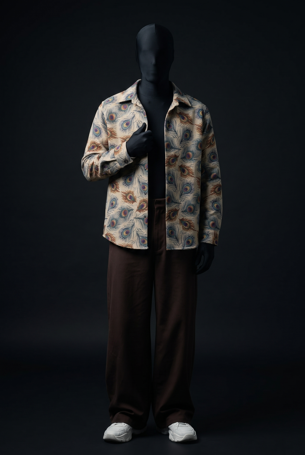 Front view of cream collared overshirt with peacock feather print, worn open over brown wide-leg trousers on a mannequin