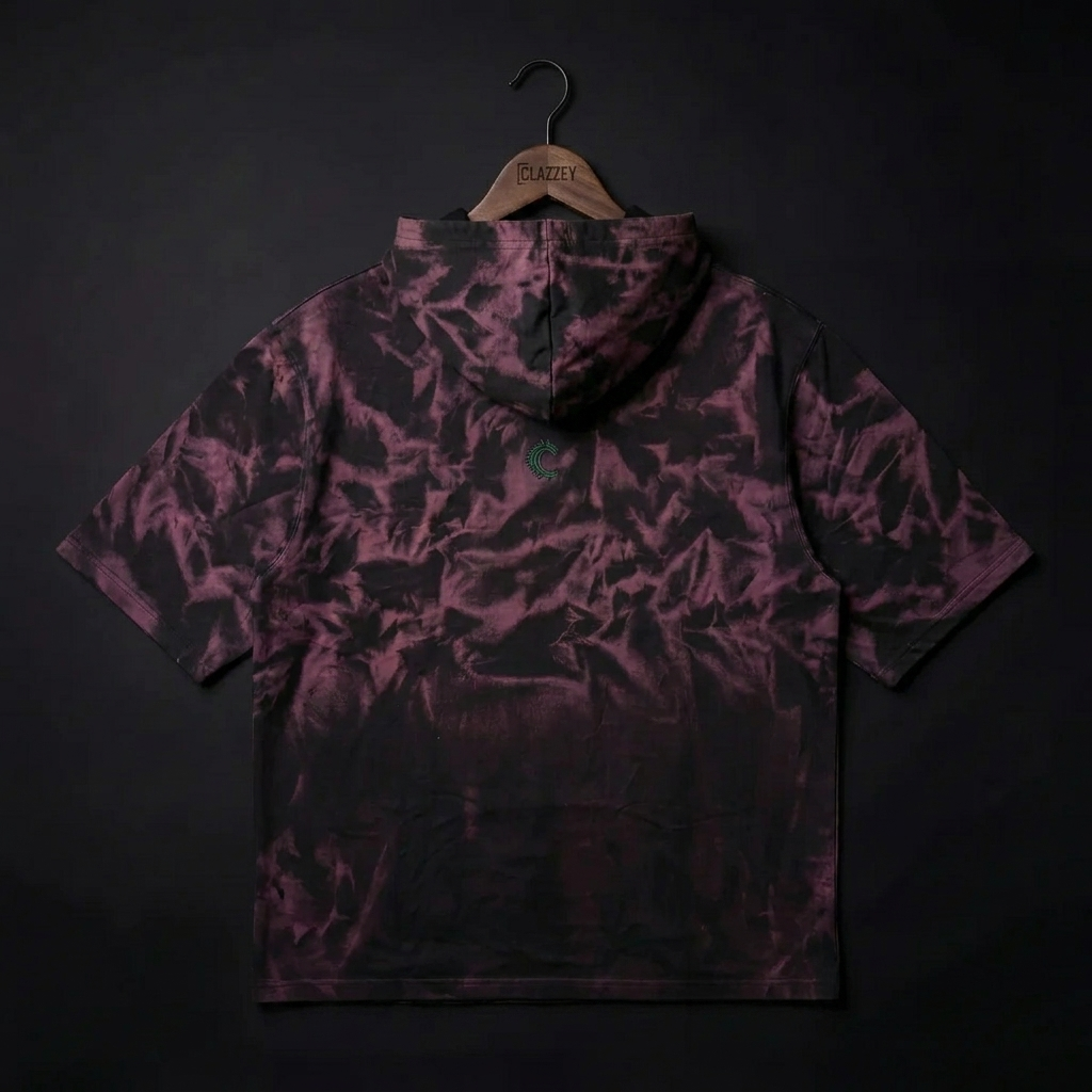 Back of short-sleeve tie-dye hoodie in black and plum, hanging on a Clazzey hanger, small green logo below hood